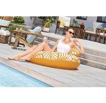 Scène extérieure avec une femme se détendant sur un îlot de piscine gonflable au bord de la piscine.