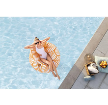 Femme se détend sur une bouée dans la piscine, avec des serviettes et des boissons au bord de la piscine