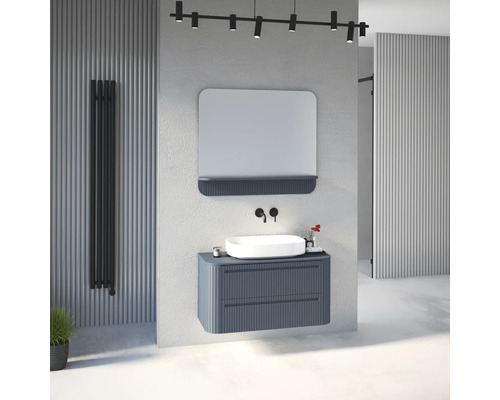 Modernes Badezimmer mit blauem Unterschrank in Riffeloptik, weißem Aufsatzwaschbecken, schwarzer Wandarmatur, Spiegel und schwarzem Heizkörper.