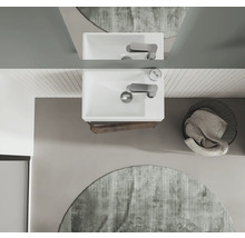 Vue de dessus d'une salle de bains avec lavabo, robinet, miroir, tapis rond et panier à linge