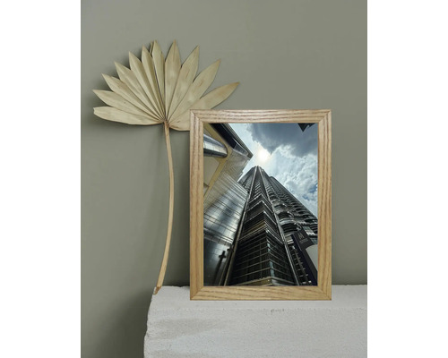 Dekorativer Rahmen mit einem Bild der Petronas Twin Towers und einem getrockneten Palmenblatt