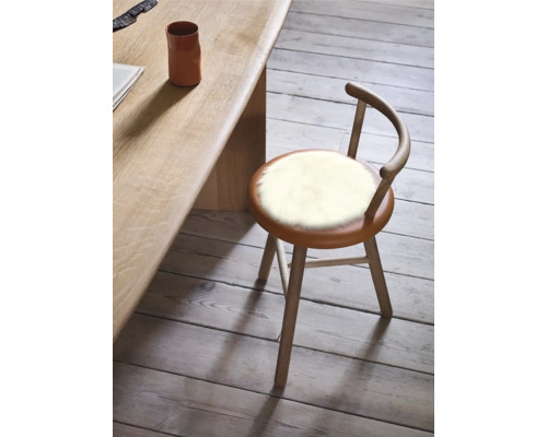 Tabouret en bois avec revêtement en fourrure à côté d'une table en bois