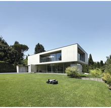 Robot tondeuse à gazon devant une maison moderne