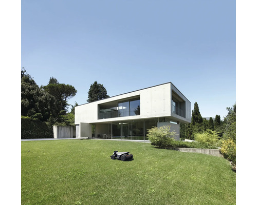 Robot tondeuse à gazon devant une maison moderne