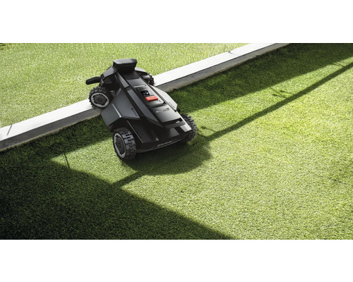 Robot tondeuse à gazon sur gazon à côté de la bordure