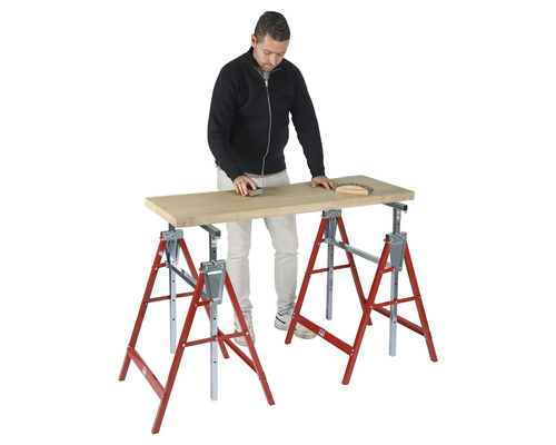 Homme ponçant une planche de bois sur deux tréteaux pliants rouge et argent