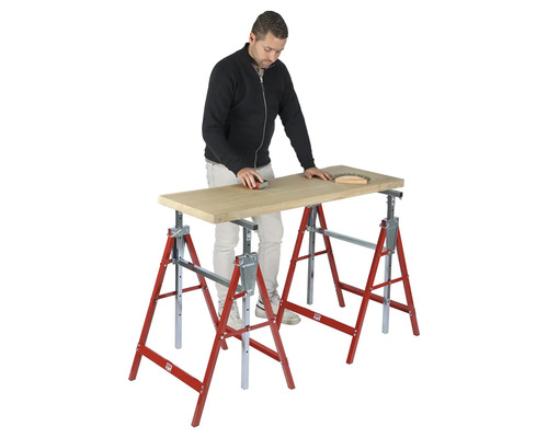 Un homme ponce une planche en bois sur deux tréteaux pliants rouges et argentés