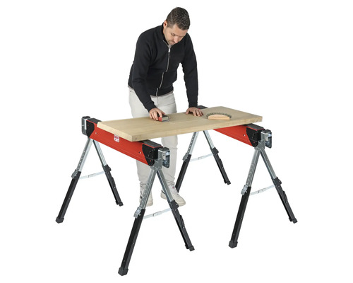 Un homme ponce une planche de bois sur un tréteau de table de travail réglable.