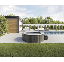 Bain à remous gonflable dans le jardin à côté d'une piscine et d'une terrasse avec mobilier de jardin.