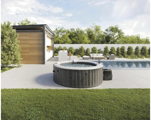 Bain à remous gonflable dans le jardin à côté d'une piscine et d'une terrasse avec mobilier de jardin.