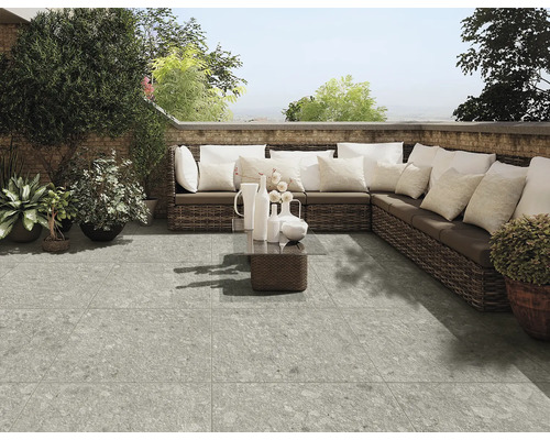 Terrasse mit grauem Plattenboden, Rattansofa und Dekoration