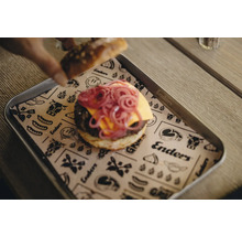 Un hamburger avec des oignons rouges et du fromage sur un plateau avec un dessous de plat en papier.