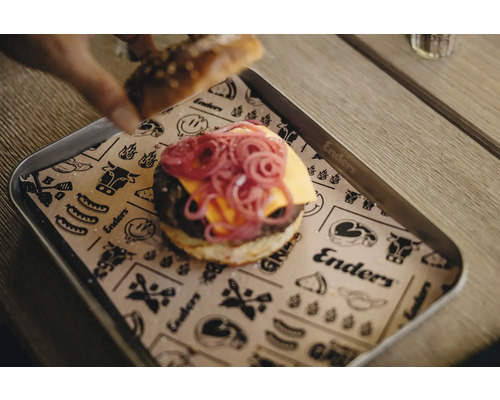 Un hamburger avec des oignons rouges et du fromage sur un plateau avec un dessous de plat en papier.