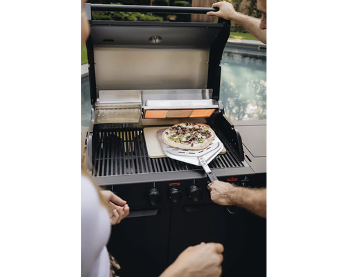 Person bereitet Pizza auf einem Cruster Gasgrill zu