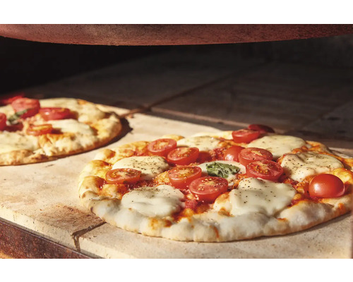 Deux pizzas aux tomates et à la mozzarella dans un four à pizza.