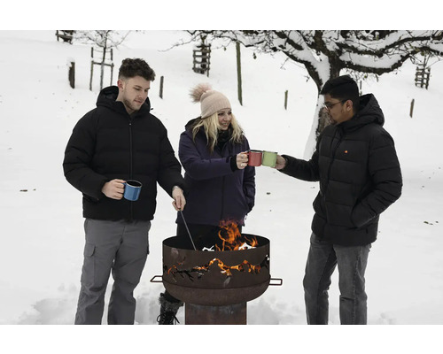 Trois personnes se tiennent dans la neige autour d'un foyer avec des tasses à la main.