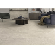 Salon lumineux avec carrelage de sol gris clair aspect marbre, canapé, fauteuil et table.