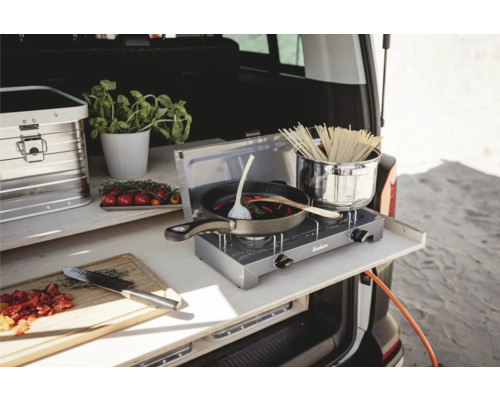 Cuisine de camping dans le coffre avec plaque de cuisson, poêle, casserole et ingrédients