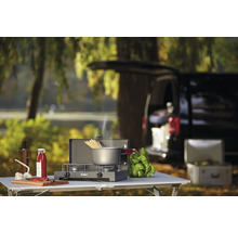 Réchaud de camping avec casserole, ingrédients et voiture en arrière-plan