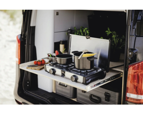 Cuisine de camping dans le coffre d'un van avec réchaud à gaz et casseroles