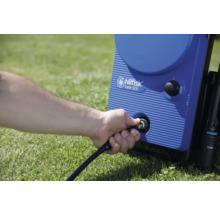 Un homme connecte le tuyau à un nettoyeur haute pression Nilfisk Core 125.