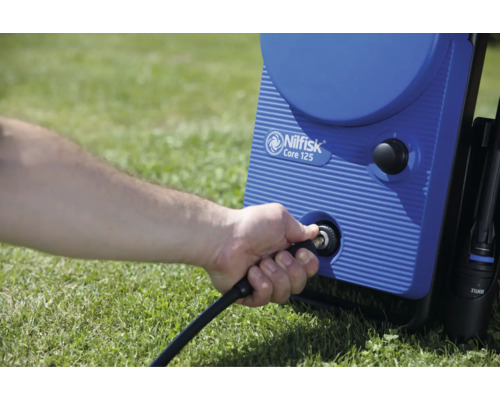 Un homme connecte le tuyau à un nettoyeur haute pression Nilfisk Core 125.