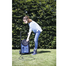 Femme utilisant un nettoyeur haute pression bleu dans le jardin