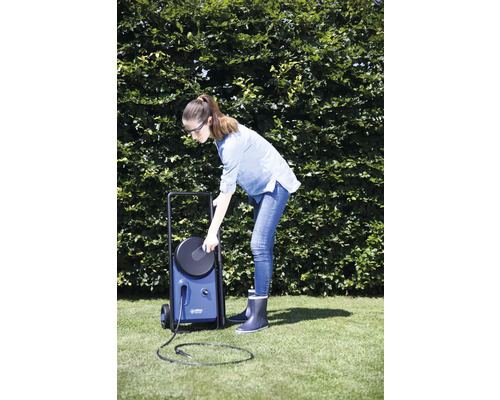 Femme utilisant un nettoyeur haute pression bleu dans le jardin