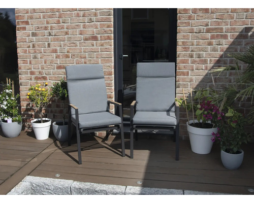 Zwei Gartenstühle mit hohen Rückenlehnen und grauen Polstern auf einer Terrasse.