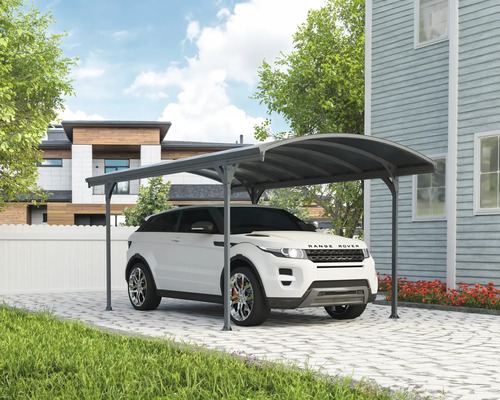 Auto unter einem Carport auf einer gepflasterten Auffahrt vor einem Haus