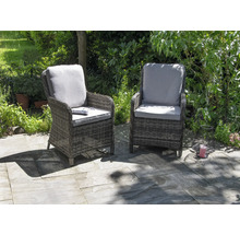 Zwei Rattan-Gartenstühle mit Kissen stehen auf einer Terrasse.