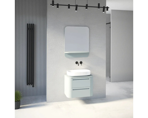 Salle de bains moderne aspect béton avec meuble vert menthe, vasque à poser blanche, miroir, robinetterie murale noire et radiateur.