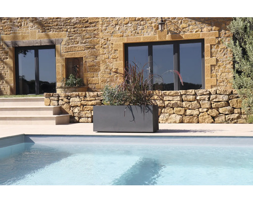 Jardinière grise avec plantation à côté d'une piscine devant une maison