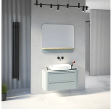 Salle de bain moderne avec meuble sous-vasque nervuré vert clair, vasque à poser blanche, robinetterie murale noire et miroir avec étagère.