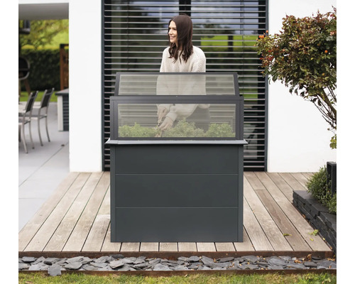 Jardinière surélevée avec couvercle transparent et femme jardinant sur une terrasse en bois