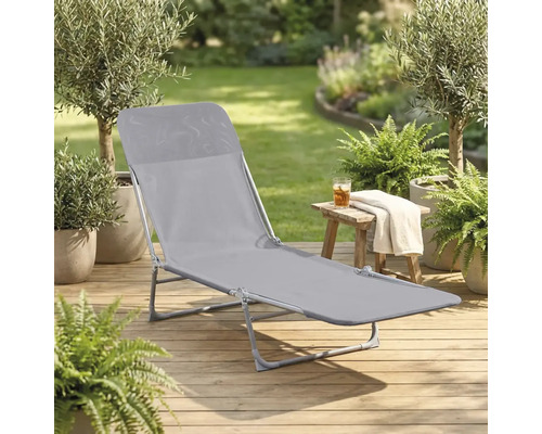 Chaise longue de jardin grise sur une terrasse en bois dans un jardin
