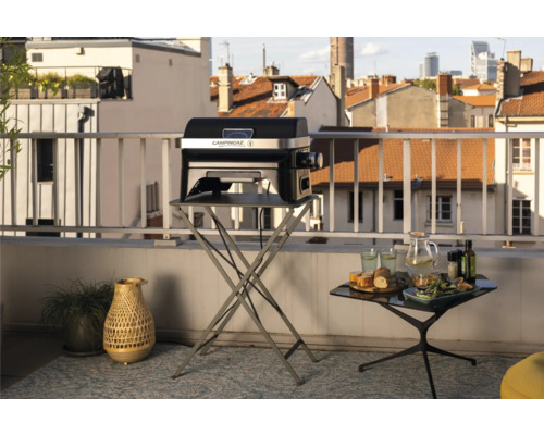 Scène de balcon avec un barbecue CampinGaz sur une table pliante et une table avec de la nourriture et des boissons.