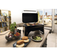 Gril de table électrique avec couvercle ouvert et aliments grillés sur une table à manger