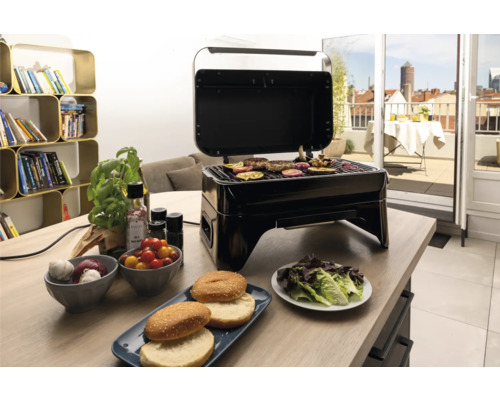 Gril de table électrique avec couvercle ouvert et aliments grillés sur une table à manger
