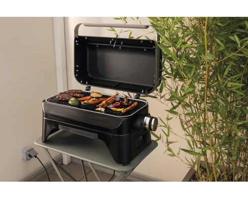 Barbecue électrique avec couvercle ouvert sur une table avec des aliments grillés