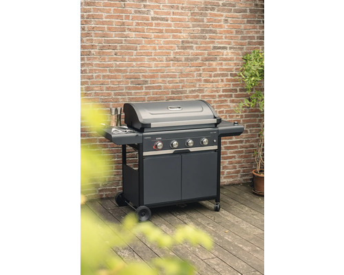 Barbecue à gaz avec quatre brûleurs, étagères et meuble bas sur une terrasse