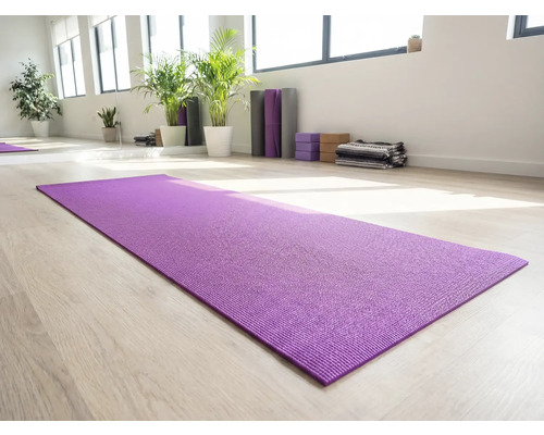 Lila Yogamatte auf hellem Holzboden in einem hellen Raum mit Yogazubehör