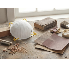 Masque antipoussière, papier abrasif et outils sur un établi