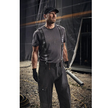 Homme en vêtements de travail avec bretelles et casquette tenant un tuyau