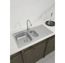 Küchenspüle aus Edelstahl mit Abtropffläche und Wasserhahn auf einer Küchentheke.