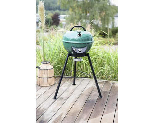 Grüner Kugelgrill auf einer Holzterrasse im Garten.