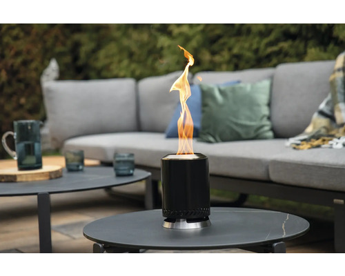 Cheminée de table à l'éthanol sur une table de jardin avec des meubles de salon à l'arrière-plan