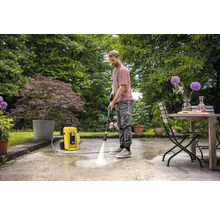 Mann reinigt Terrasse mit Hochdruckreiniger im Garten.