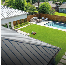 Vue d'un jardin avec robot tondeuse, espace barbecue, table à manger et piscine.