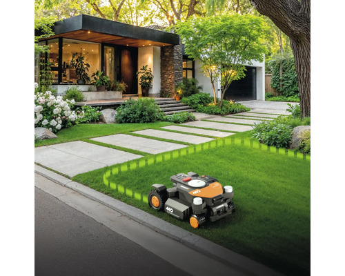 Robot tondeuse en action devant une maison moderne avec un jardin bien entretenu
